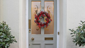 A white door with a glass panel, a wreath, and a doormat with a Christmas design. - Kingston House (Torquay)