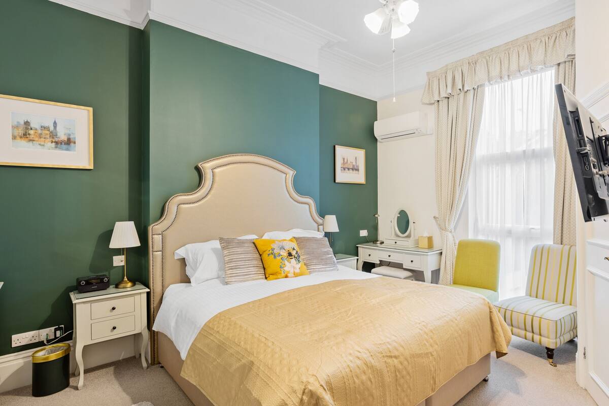 A neatly arranged bedroom with a large bed, bedside tables, a chair, and a dresser.