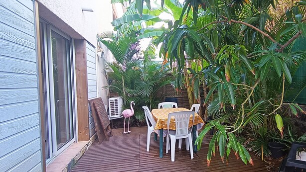 Une terrasse avec une table et des chaises, entourée d’une végétation tropicale luxuriante.