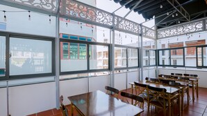 Un espace repas avec des tables et des chaises, de grandes fenêtres et des éléments décoratifs en métal.