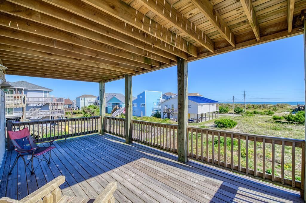 A wooden deck with a view of houses and beach.