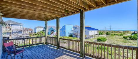 A wooden deck with a view of houses and beach.
