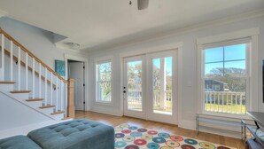 Ein geräumiges Wohnzimmer mit einem blauen Sofa, einem bunten Teppich und einer Treppe.