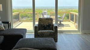 Una habitación con un gran ventanal corredera que da a una terraza exterior con vistas al océano.