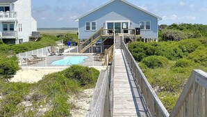 Una propiedad frente al mar con una terraza de madera que conduce a una casa con piscina.