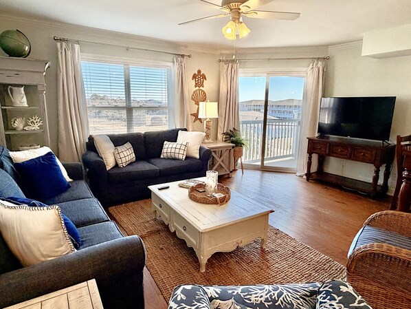 A living room with a sofa, coffee table, TV, and a balcony with a view.