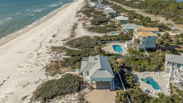 An aerial view of a coastal property with a beach, a swimming pool, and multiple houses. - A GREAT ESCAPE is yours.....beachfront! Leave the hustle and bustle of the city! (St. George Island)