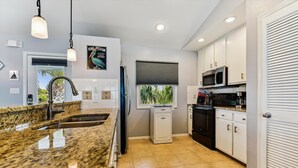 A modern kitchen with granite countertops, stainless steel appliances, and a window with a view of palm trees. - A GREAT ESCAPE is yours.....beachfront! Leave the hustle and bustle of the city! (St. George Island)