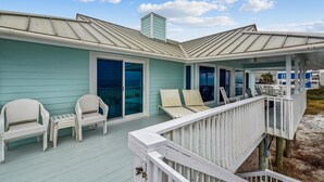 A coastal house with a covered porch, sliding glass doors, and outdoor seating. - A GREAT ESCAPE is yours.....beachfront! Leave the hustle and bustle of the city! (St. George Island)