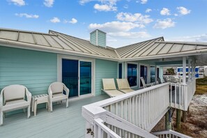 Ein Küstenhaus mit überdachter Veranda, Schiebegläsern und Sitzgelegenheiten im Freien.