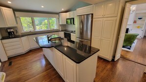 Una cocina moderna con armarios blancos, encimera negra y refrigerador de acero inoxidable.