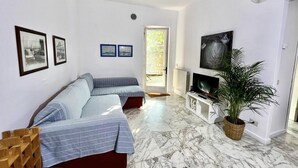 Un soggiorno moderno con un divano, una TV e una pianta.