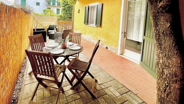 Un patio con tavolo e sedie, un albero e un muro giallo.