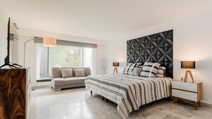 Une chambre à coucher comprenant un lit, un canapé, une table de chevet, une lampe et une armoire.