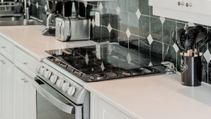 Une cuisine moderne avec des meubles blancs, un dosseret en carreaux noirs et des appareils électroménagers en acier inoxydable.