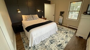 A bedroom with a bed, nightstands, a ceiling fan, a window, and a mirror. - Highland Hills- Family, Farm, Golf and Goats (Ubly)
