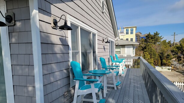A wooden deck with outdoor seating and a railing. - 6 Bedroom ocean block home with private beach access (Bethany Beach)
