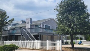 A two-story house with a balcony, a white picket fence, and a tree. - 6 Bedroom ocean block home with private beach access (Bethany Beach)