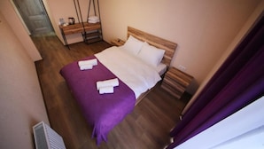 Un dormitorio con una cama de madera, una colcha morada y una mesita de noche con una lámpara.