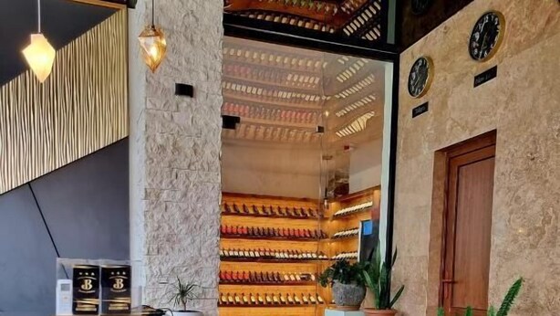 Una moderna zona de recepción con suelo de mármol, un mostrador de madera y una pared decorada con relojes.
