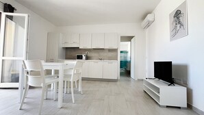 Una cucina moderna con mobili bianchi, un forno a microonde e un'area pranzo con sedie bianche.