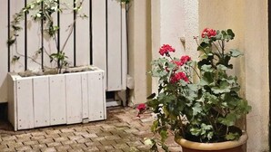 Uma área de recepção com placa, luminária pendente, planta em vaso e tapete vermelho.