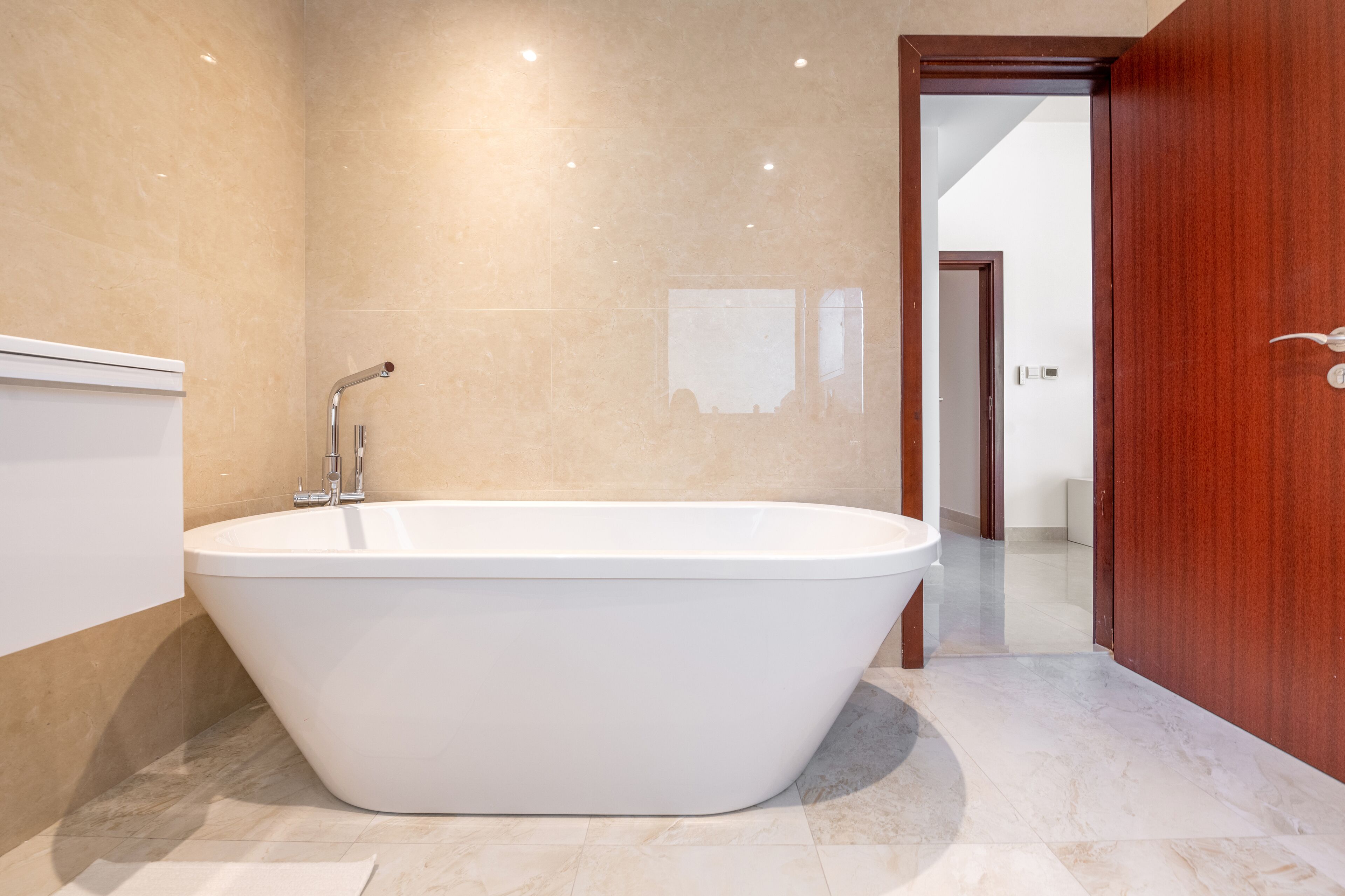 Une salle de bain moderne avec une baignoire sur pieds, une porte en bois et un sol carrelé.
