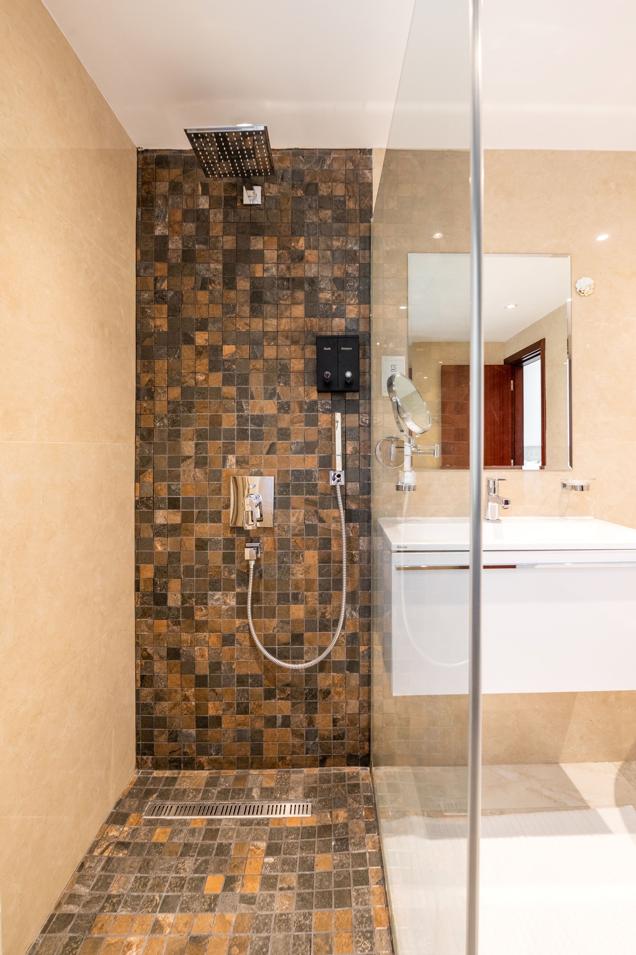 A modern bathroom with a shower, a glass-enclosed vanity, and a tiled backsplash.