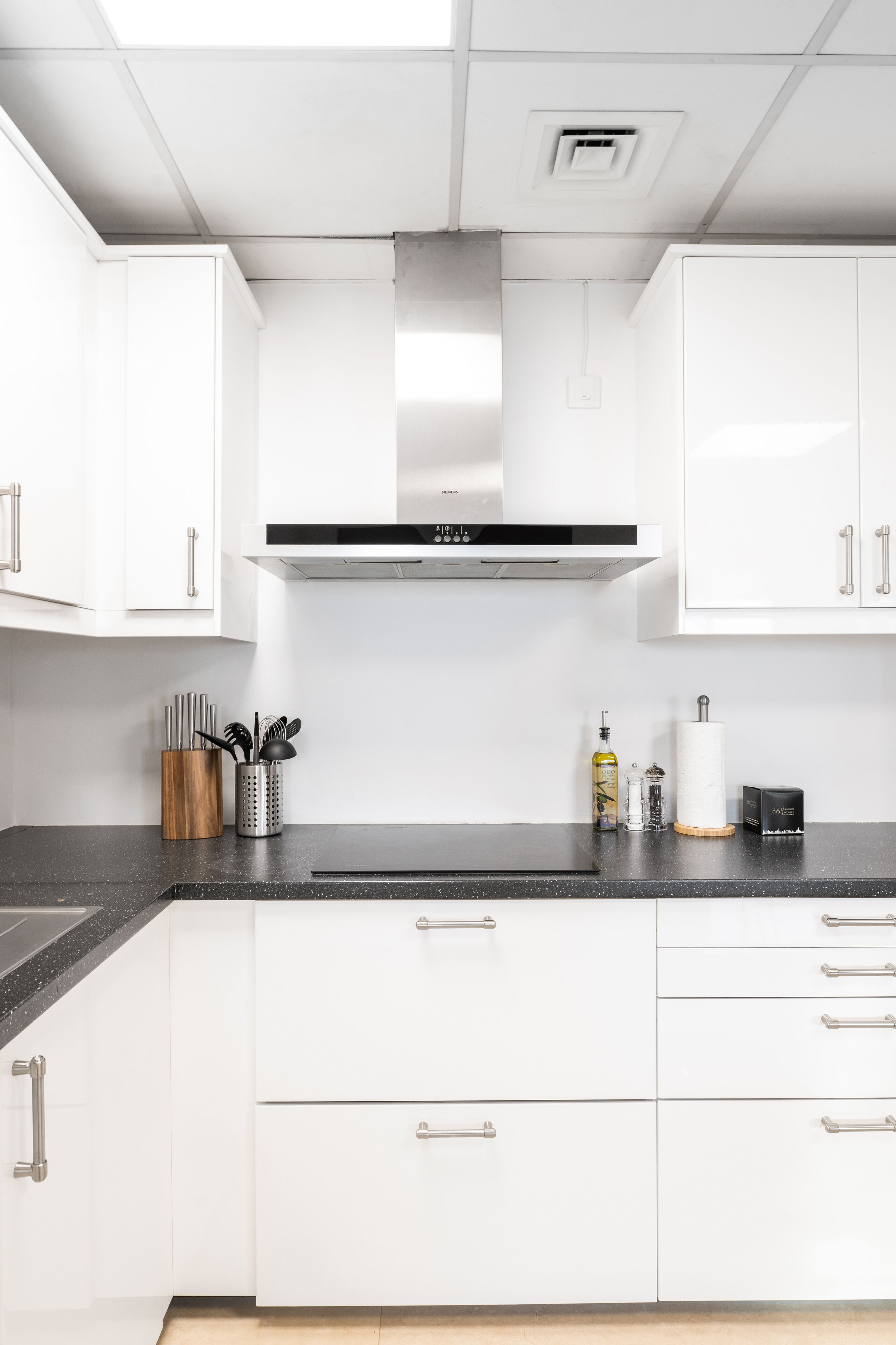 A modern kitchen with white cabinets, a black countertop, and stainless steel appliances.