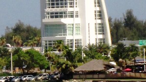 A modern, white, multi-story building with a unique curved roof, surrounded by greenery and parked cars. - Pool home > 1/2 miles to beach 1 mile to Port Watch Rockets take off and land (Cape Canaveral)