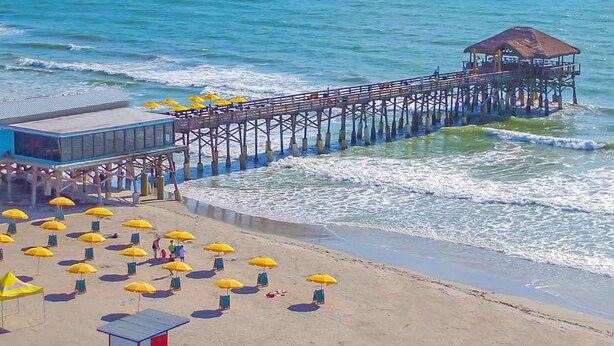 A beach with a pier, beach umbrellas, and a lifeguard tower. - Pool home > 1/2 miles to beach 1 mile to Port Watch Rockets take off and land (Cape Canaveral)