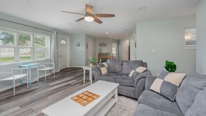 A spacious living room with a grey sectional sofa, a white coffee table, and a ceiling fan. - Pool home > 1/2 miles to beach 1 mile to Port Watch Rockets take off and land (Cape Canaveral)