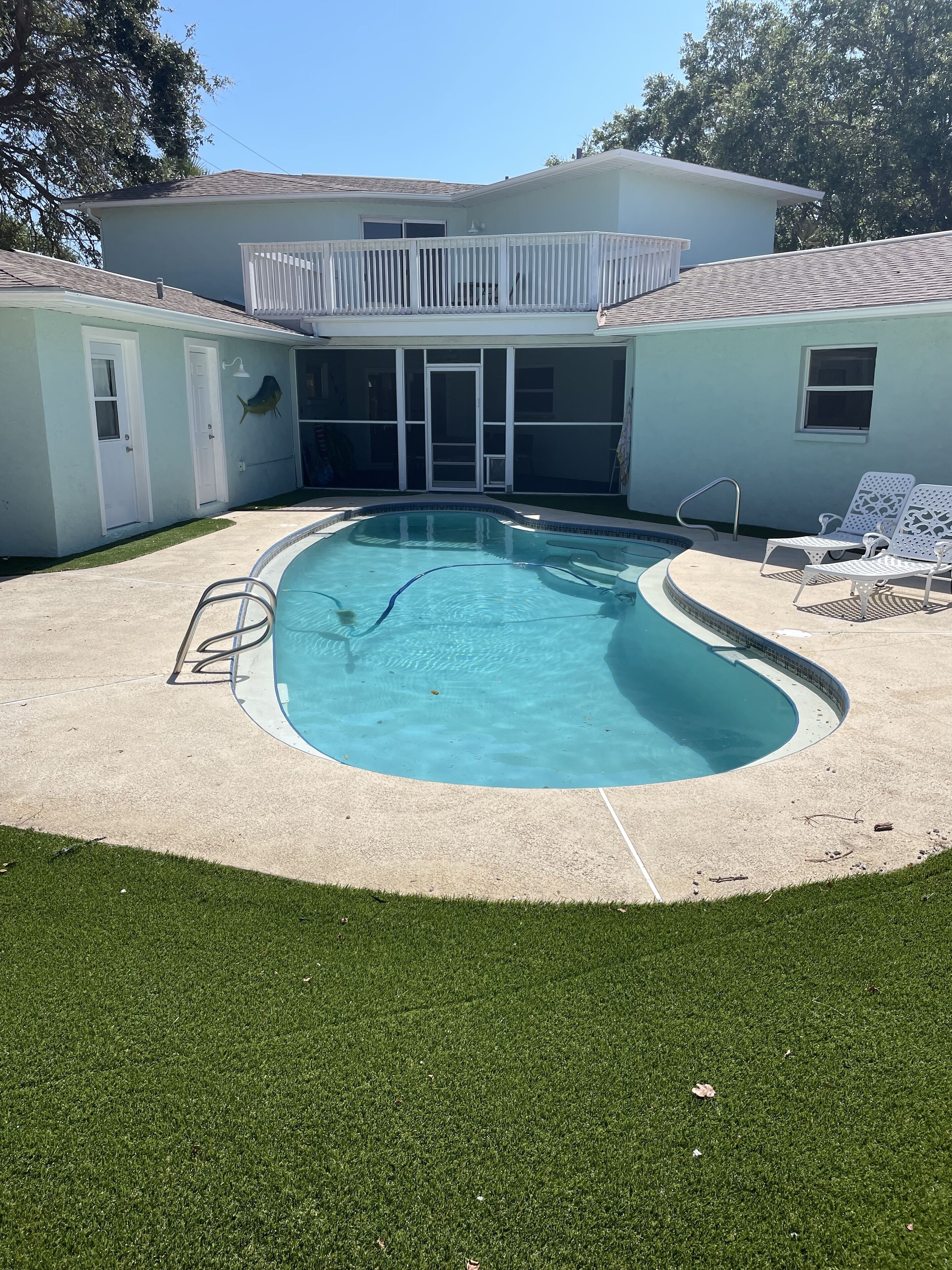 Ein Garten mit Schwimmbad, überdachter Terrasse und Rasenfläche.