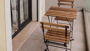 A balcony with a sliding glass door, a small table with benches, and a window. - Gold Apartment Baleal (Leiria)