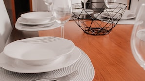 A dining table set with plates, cutlery, and wine glasses, with a geometric wire basket in the center. - Gold Apartment Baleal (Leiria)