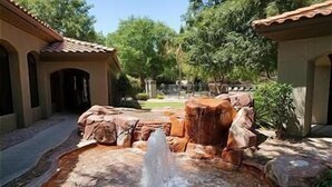 Ein angelegter Garten mit Wasserelementen, darunter ein Brunnen und Felsformationen.