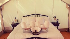 A tented room with a bed, a bedside table, and a lamp. - Get in touch with nature. (Richmond)