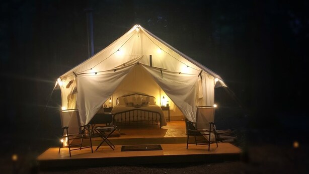 A tent with a bed, two chairs, and a table. - Get in touch with nature. (Richmond)