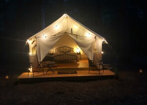 Una tenda con un letto, due sedie e un tavolo.