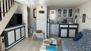 Een ruimtelijk ingerichte leefruimte met kitchenette, eethoek en een zithoek.