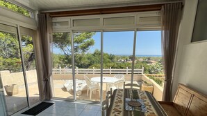 Een balkon met een tafel en stoelen, uitzicht op de zee en een witte hek.