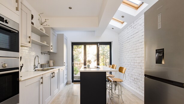 Una cocina moderna con armarios blancos, una isla central y un horno empotrado.