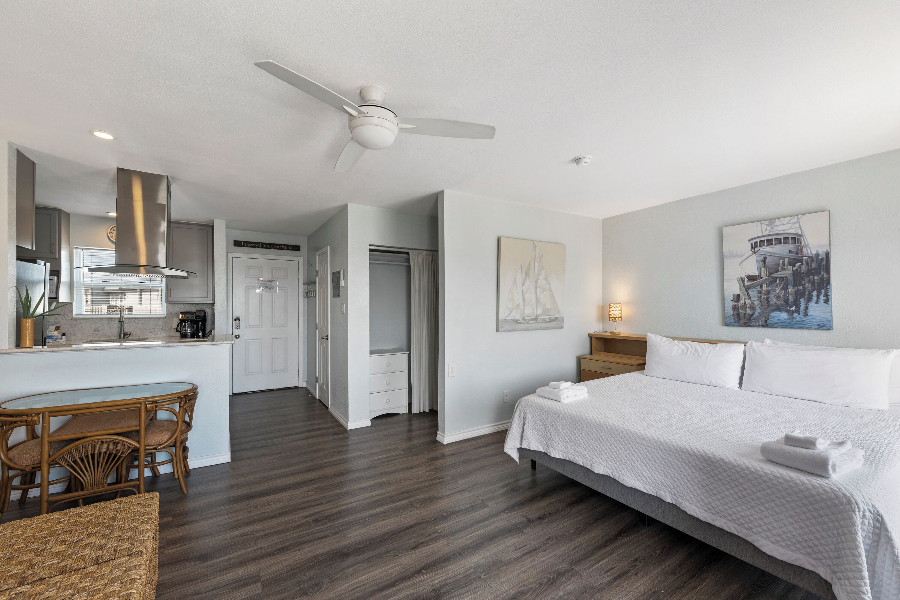 Ein Hotelzimmer mit Bett, Esstisch mit Stühlen, einer Küchenzeile und einem Deckenventilator.
