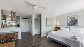 Ein Hotelzimmer mit Bett, Esstisch mit Stühlen, einer Küchenzeile und einem Deckenventilator.