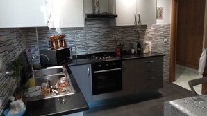 Une cuisine moderne dotée d’un îlot central, d’appareils électroménagers en acier inoxydable et d’un revêtement mural décoratif.