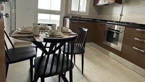 Et moderne køkken med et spisebord dækket til fire personer, udstyret med komfur, ovn og emhætte.