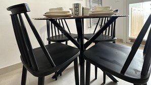 En spiseplads med et rundt bord, sorte stole og et sort-hvidt abstrakt billede på væggen.
