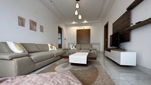 En moderne stue med sofa, sofabord og fjernsyn på et hvidt skab.