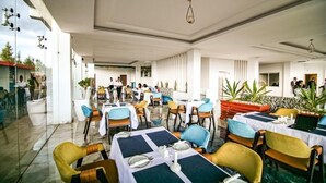 A restaurant with tables set for dining, chairs, and potted plants.