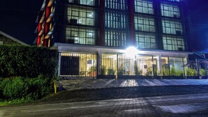 A hotel with a modern facade, illuminated signage, and a gated entrance.
